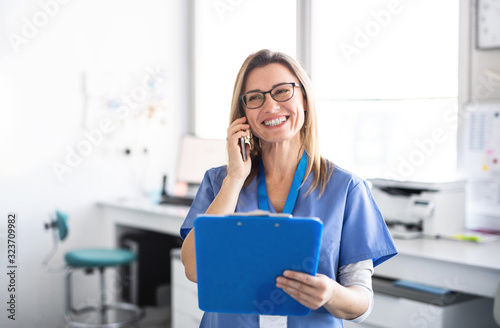A portrait of dental assistant in modern dental surgery, using smartphone.