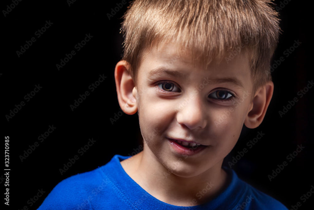 Portrait of the boy 's smiling child close-up against a black background Portrait of the boy 's smiling child close-up against a black background
