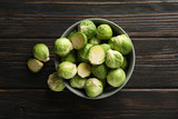 Bowl with brussels sprout on wooden background, top view