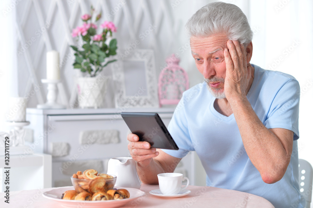Portrait of senior man reading article from tablet Portrait of senior man reading article from tablet