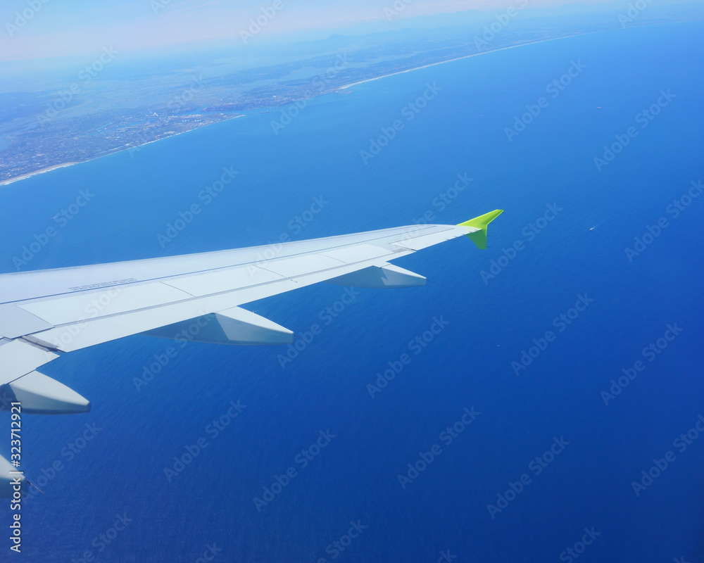 Obraz premium VIew of blue sea from an airplane window. Landscape coast, airplane wing