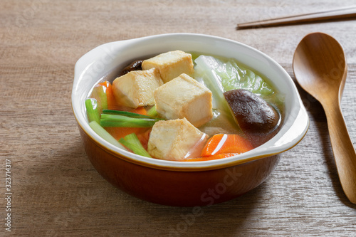 close up of fish tofu clear soup in a ceramic bowl on wooden table. asian homemade style food concept.