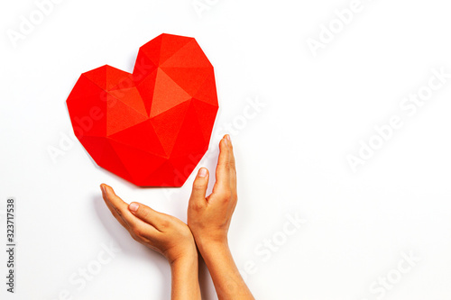 Hands holding red polygonal paper heart shape over white background