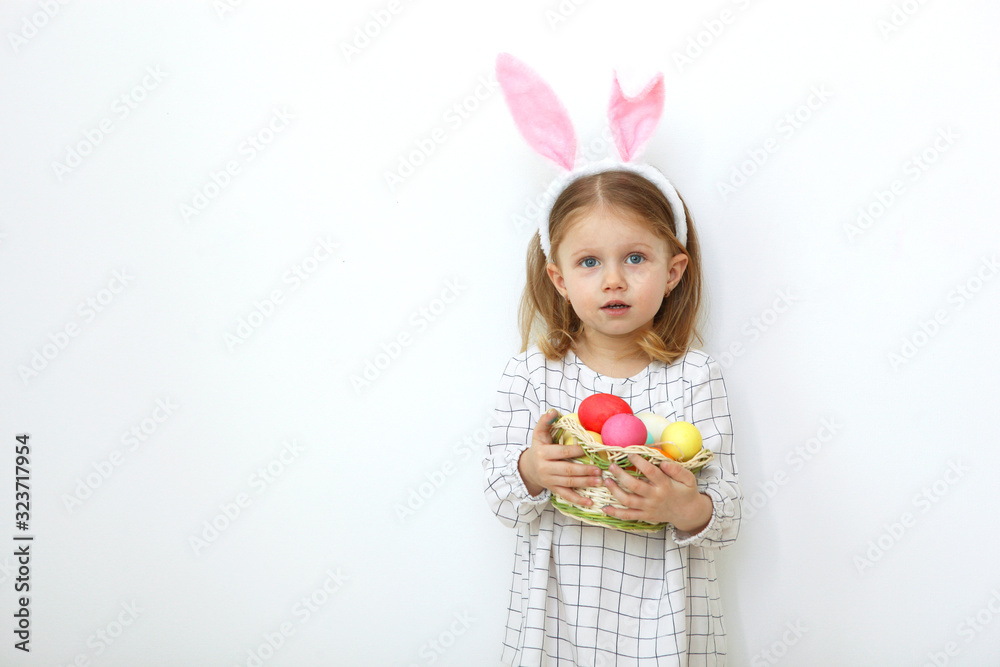 Cute little girl with easter basket on a light background. Place to insert text. Easter traditions. Happy easter! Cute little girl with easter basket on a light background. Place to insert text. Easter traditions. Happy easter!