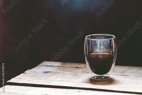 Transparent cup of espresso on a wooden table