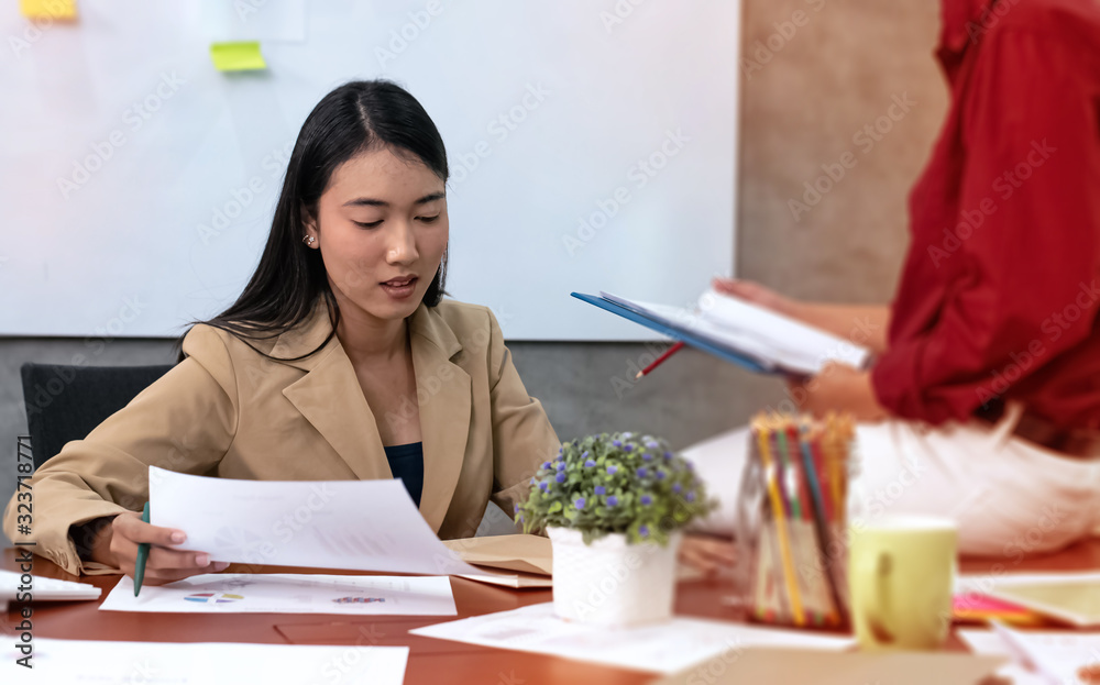 Young businesswoman working hard ,with colleagues team meeting,at office,plenty of paper chart on wooden desk Young businesswoman working hard ,with colleagues team meeting,at office,plenty of paper chart on wooden desk