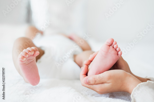 Young Asian mother holding her newborn baby with love on white bed, mother's day concept