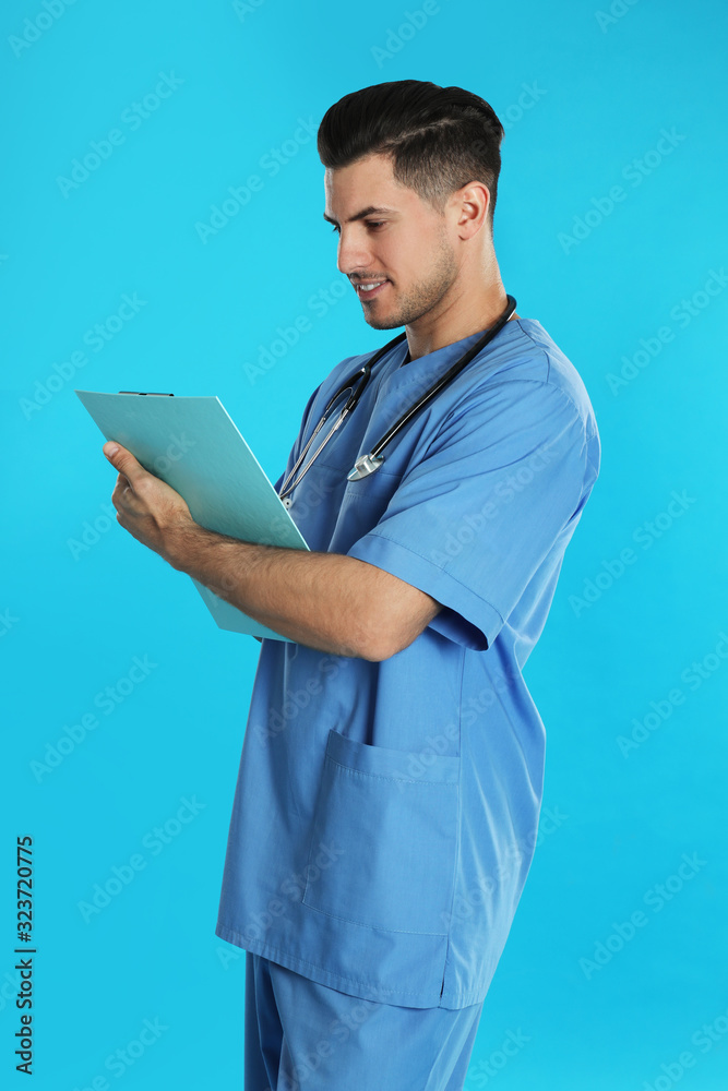 Handsome doctor with clipboard on blue background Handsome doctor with clipboard on blue background