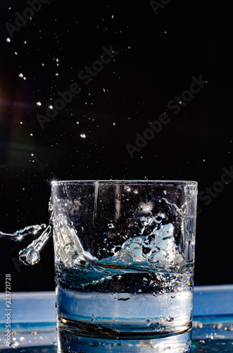 Multicolored splashes of summer. Fresh fruit and splashes of water.The photo shows a slice of green apple thrown into a glass of water. Splashes of cool drink refresh.