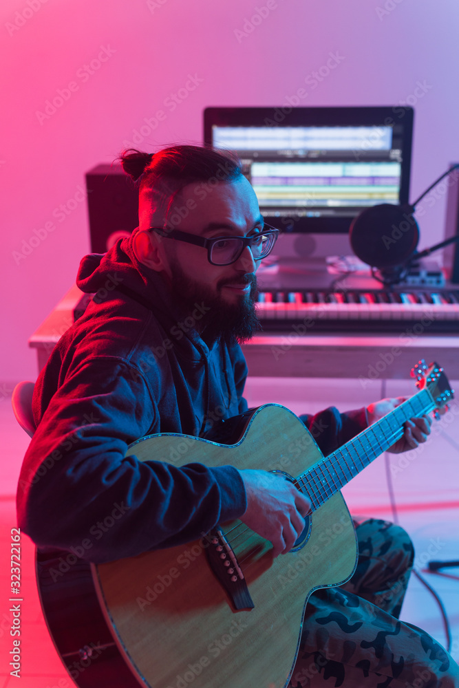Obraz premium Create music and a recording studio concept - Bearded man guitarist recording electric guitar track in home studio