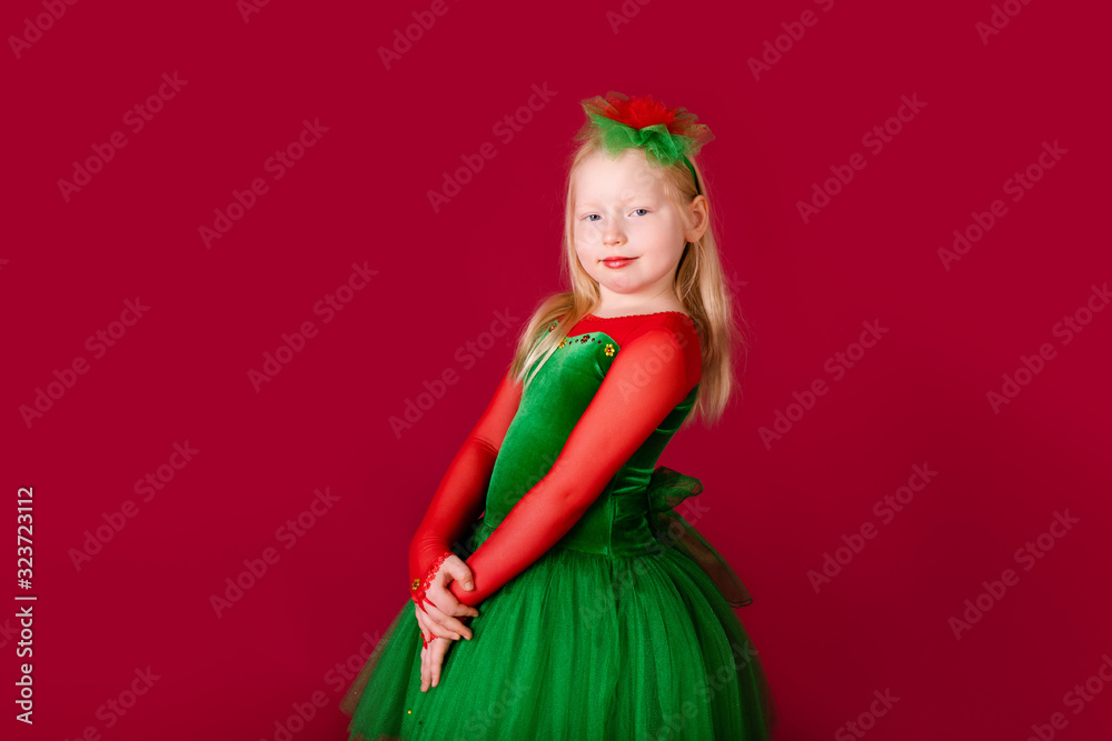 Beautiful little plump girl princess dancing in luxury green dress isolated on red background. Carnival party with costumes Beautiful little plump girl princess dancing in luxury green dress isolated on red background. Carnival party with costumes