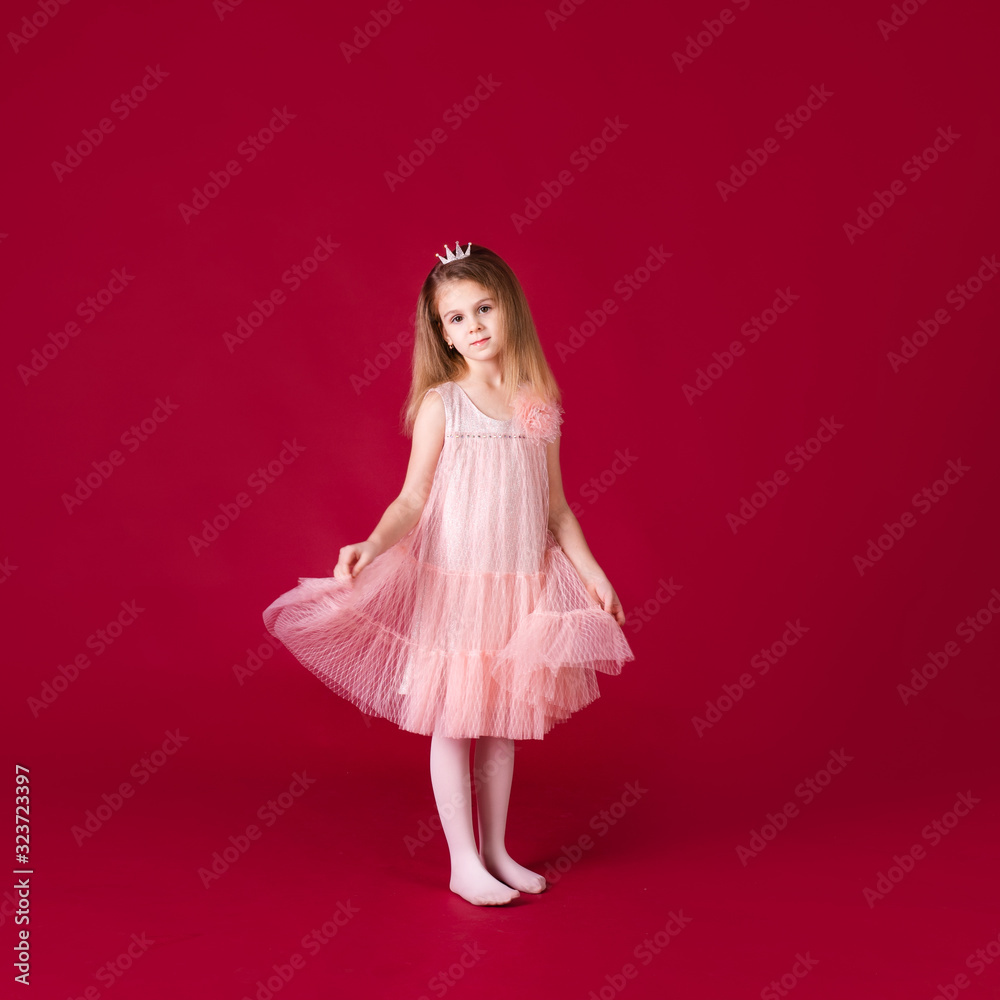 Beautiful little girl princess dancing in luxury pink and silver dress isolated on red background. Funny face, different emotions Beautiful little girl princess dancing in luxury pink and silver dress isolated on red background. Funny face, different emotions