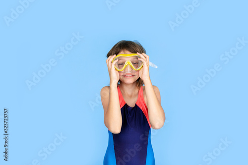 Holiday topic: child girl with snorkeling or diving equipment on a blue background. Adventure and rest concept