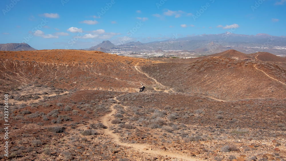 Elevated views of the arid volcanic landscape surrounding the summit of Montana Amarilla towards Pico del Teide and the small terraced villages, in Costa del Silencio, Tenerife, Canary Islands, Spain
