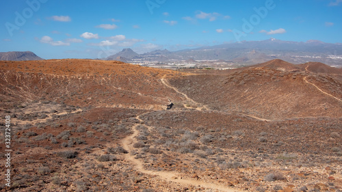 Elevated views of the arid volcanic landscape surrounding the summit of Montana Amarilla towards Pico del Teide and the small terraced villages, in Costa del Silencio, Tenerife, Canary Islands, Spain
