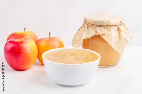 Fresh homemade applesauce in white bowl and jar with fruit puree on white table. The concept of proper nutrition and healthy eating. Organic and vegetarian food. Baby food. Copy space for text