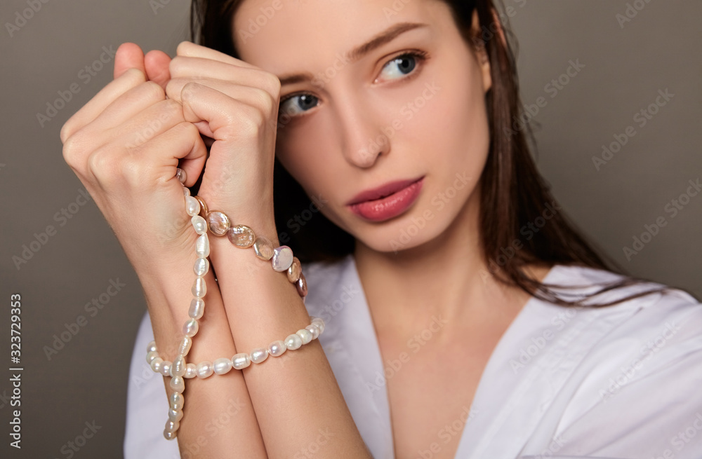 A young beautiful girl with pearls in her hands.