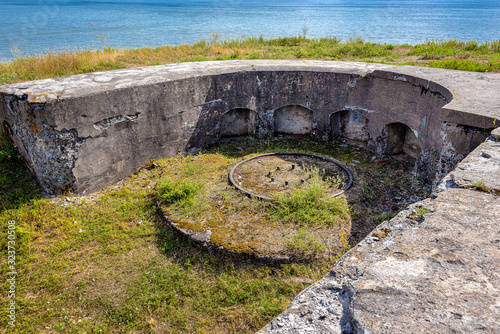 Finland, Sveaborg, Suomenlinna: Remainder of historic defencive work at the shoreline of the famous island near Finnish capital with gun pedestal, concrete wall, green grass, blue sky - war history. photo