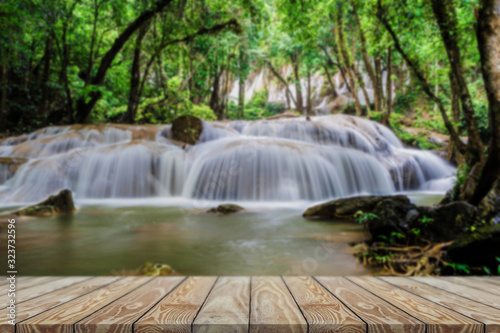 Beautiful waterfall in green forest ,Front view wood table. © vuttinan