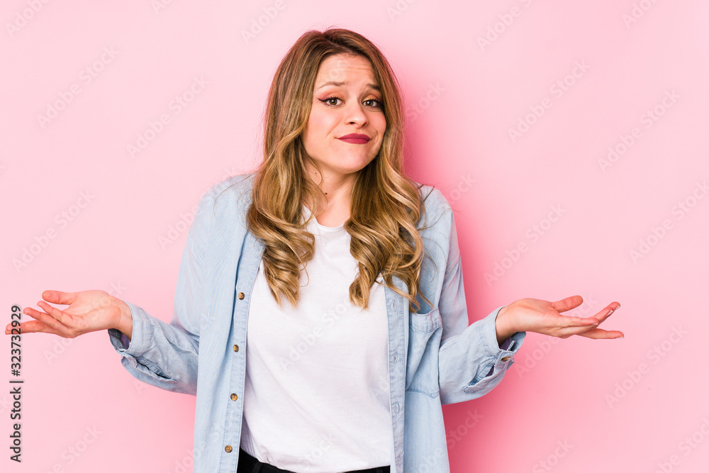 Young caucasian woman isolated on pink background doubting and shrugging shoulders in questioning gesture. Young caucasian woman isolated on pink background doubting and shrugging shoulders in questioning gesture.