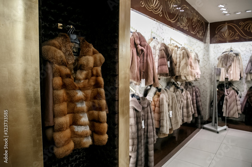 natural fur coats hang on hangers in a store. Sale of winter warm clothes. Turkish shop
