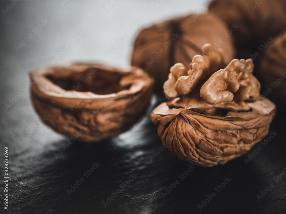 Fototapeta premium Whole walnuts on dark board. Walnut kernels on dark background. Healthy food nuts.