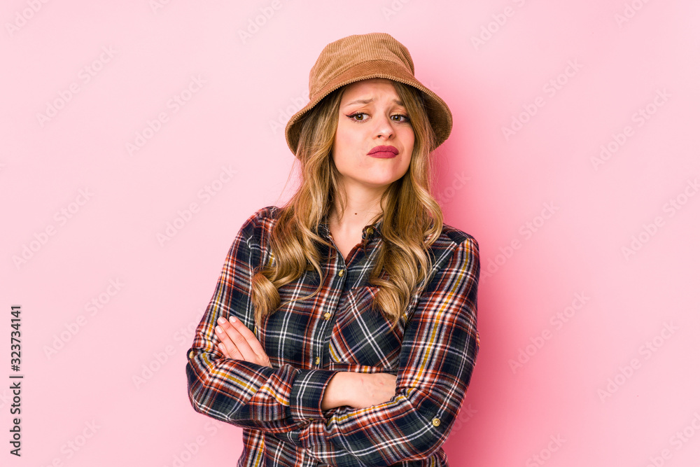 Young caucasian woman wearing a hat isolated suspicious, uncertain, examining you. Young caucasian woman wearing a hat isolated suspicious, uncertain, examining you.
