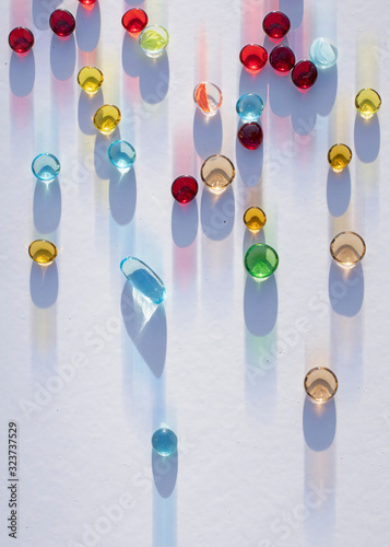 Perles de couleur en verre qui tombent avec reflets et ombres projetés par le soleil. photo
