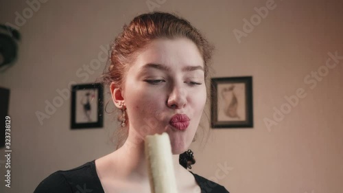 Caucasian girl with mysterious facial expression erotically eats banana. 