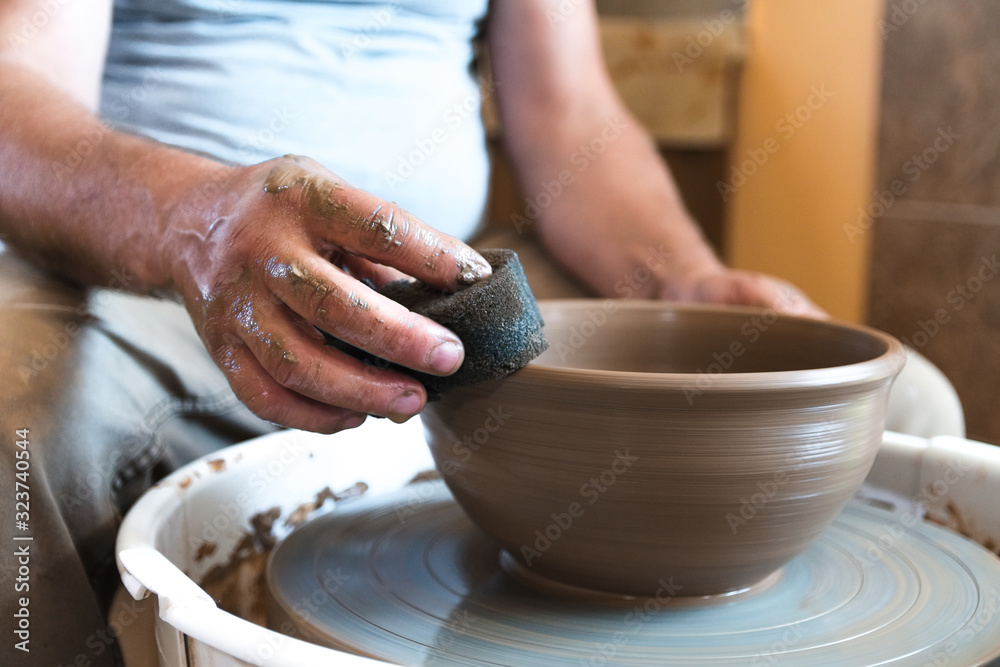 Master potter works with clay in pottery workshop.