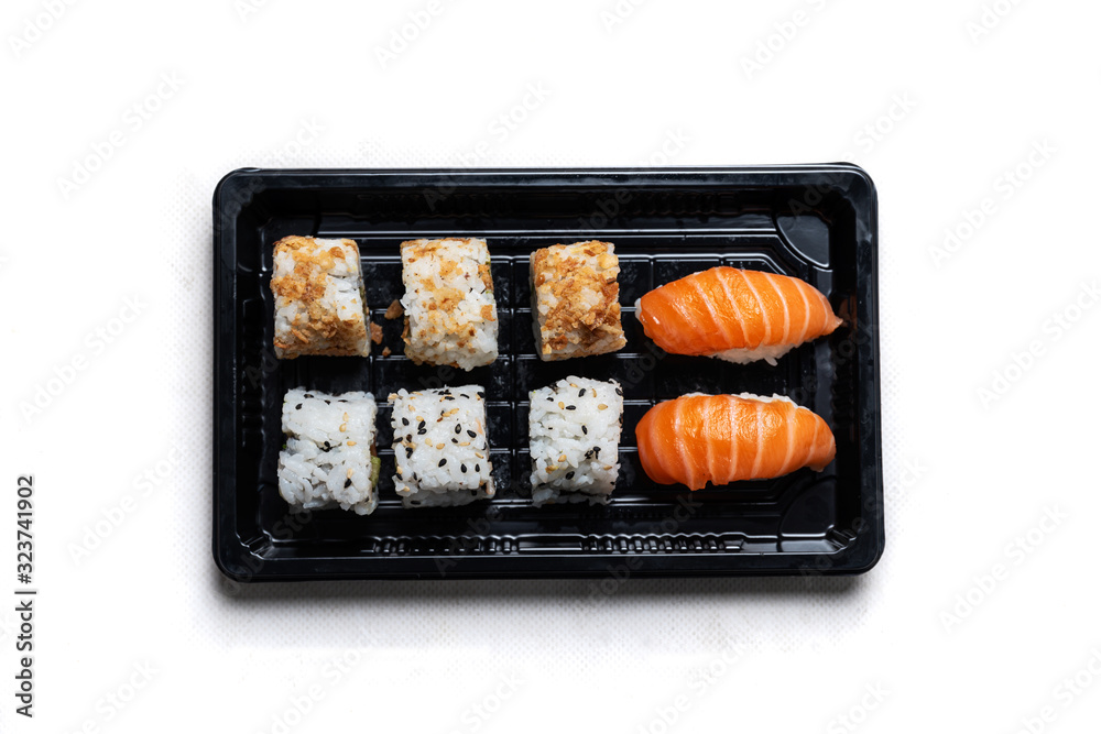 Stock photo of sushi tray with California Roll and Maki on a black recycling tray, located on a wooden table. Japanese gastronomic dish on recyclable surface. Stock photo of sushi tray with California Roll and Maki on a black recycling tray, located on a wooden table. Japanese gastronomic dish on recyclable surface.