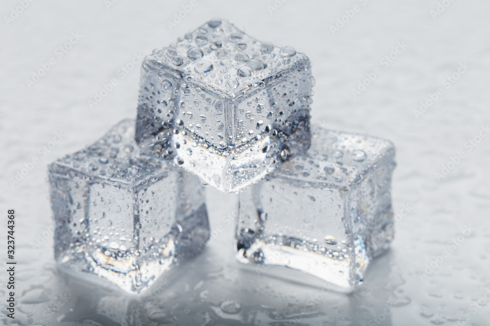 Ice cubes in the form of a pyramid with water drops close - up in macro on a white background. Ice cubes in the form of a pyramid with water drops close - up in macro on a white background.