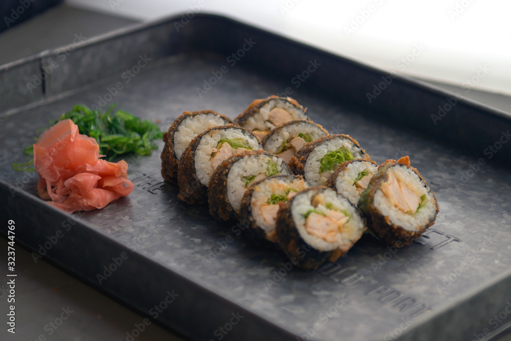 Sushi meal with ginger and wasabi on a metal plate. Sushi Set - Different Types of Maki Sushi and Nigiri. Restaurant menu with fish food. Sushi meal with ginger and wasabi on a metal plate. Sushi Set - Different Types of Maki Sushi and Nigiri. Restaurant menu with fish food.