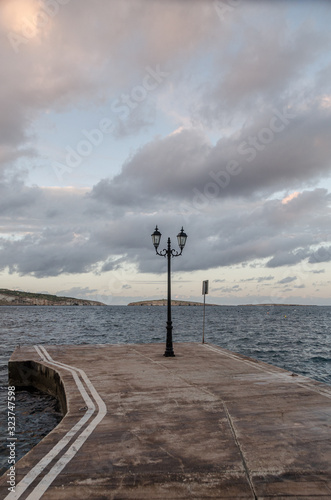 Lantern standing alone on a pier surrounded by white clouds.