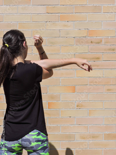 Mujer joven haciendo yoga con camisa negra y fondo de ladrillo