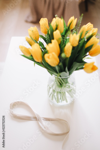 8 March, International Womens Day. Figure eight of ribbon with beautiful yellow tulips on white background. Space for text