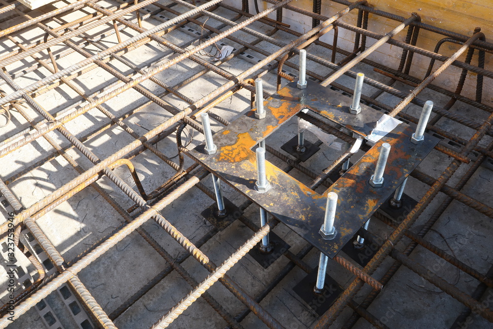 Construction site for a building with a steel structure. Plates with anchor bolts for mounting steel columns on a reinforced concrete foundation.