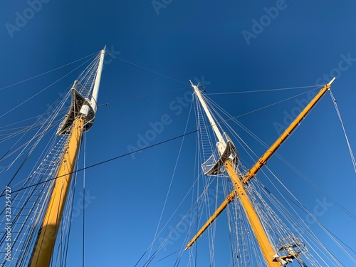 Wooden ship masts in the blue sky background