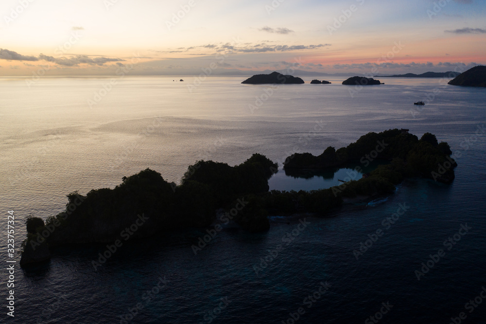 Dawn illuminates the serene waters surrounding limestone islands in Raja Ampat, Indonesia. This remote region is known as the heart of the Coral Triangle due to its incredible marine biodiversity.