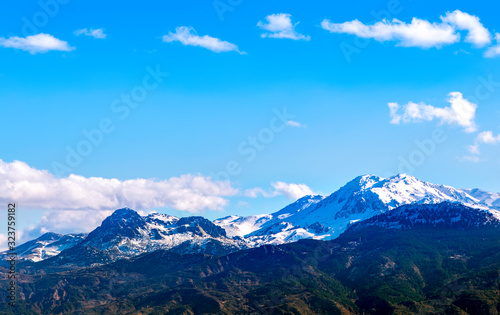 Snowy mountains and blue sky with clouds.