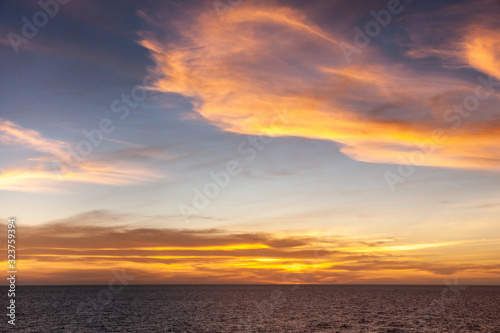 Arafura Sea, Australai - December 2, 2009: Red sunset with brown to orange and yellow clouds in light to dark blue sky. © Klodien