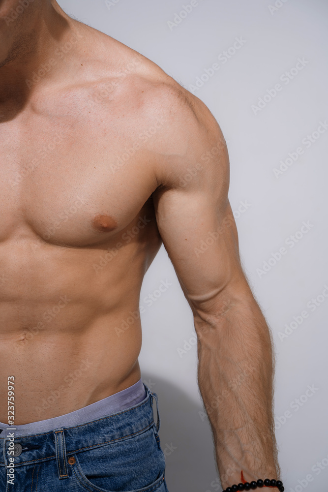 Fototapeta premium Muscular and fit young bodybuilder posing demonstrates the core muscles.