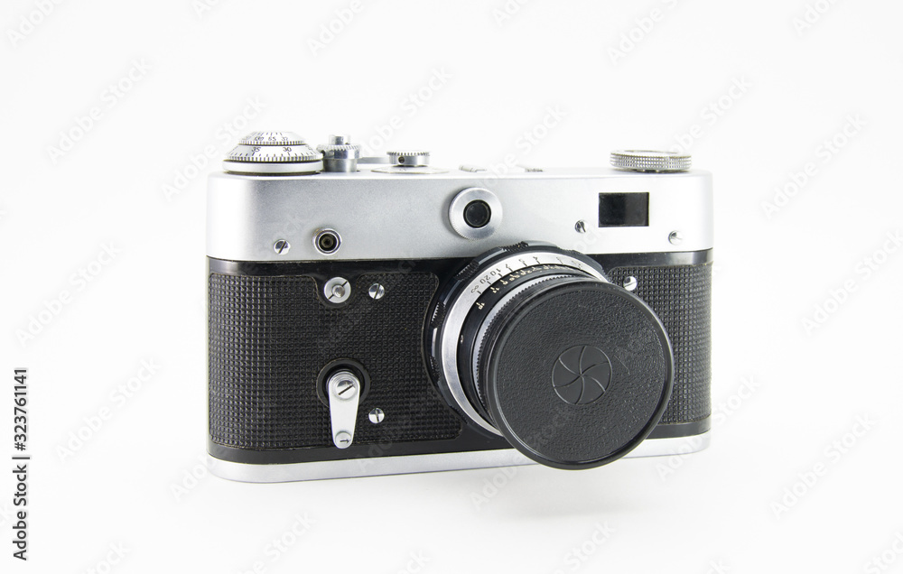 Old film retro camera with lens closed cap. Metallic black. White isolated background. Front side view