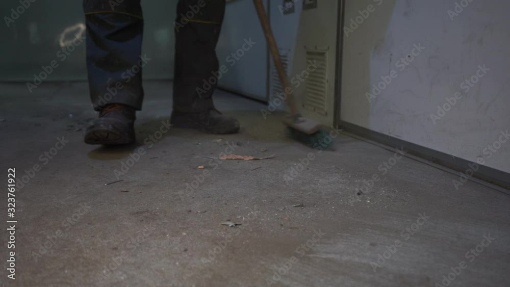 Worker sweeping dirty floor. Work boots. Work clothes. Slow motion Worker sweeping dirty floor. Work boots. Work clothes. Slow motion