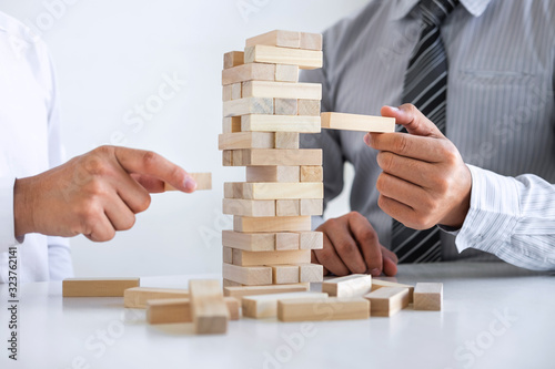 Planning Risk and Strategy in Business, Image of two Businessman hand placing making wooden block structure growing up the tower and protection to planning and development to successful