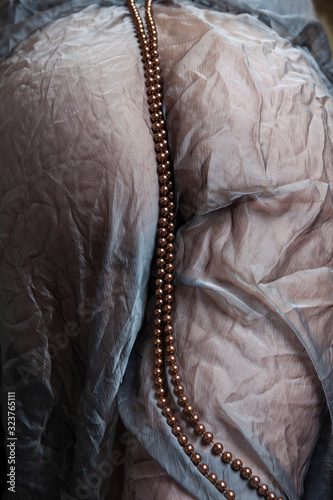 close up del fondo schiena di una donna rivestito di tessuto trasparente e collana di perle