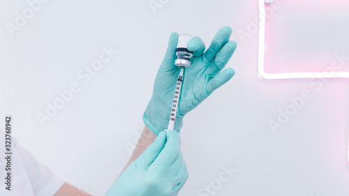 Close-up of female doctor hand with protective rubber gloves holding syringe with vaccine.