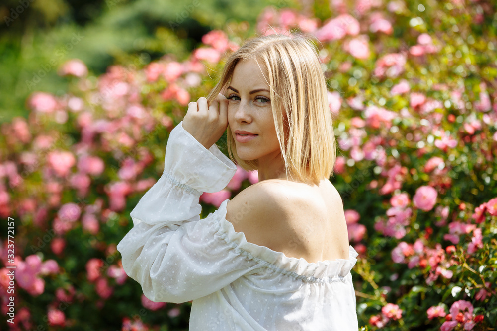 girl in a white dress in the garden with pink roses girl in a white dress in the garden with pink roses