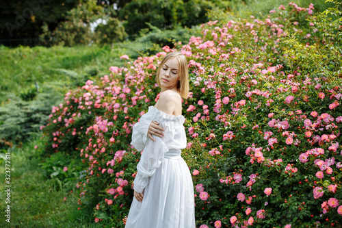 girl in a white dress in the garden with pink roses