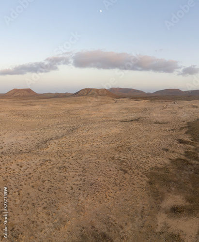 Vertical desert panorama with sand dunes  volcano mountains and the moon